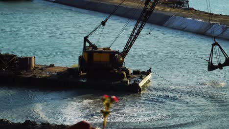 barge positioned on the sea with a crane to dredge the seabed