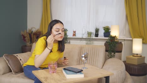 young woman is applying mascara to her eyes.