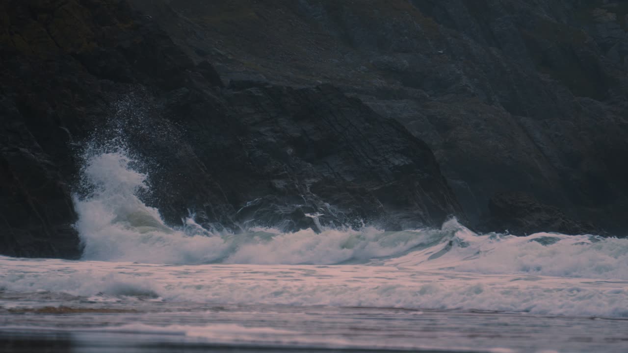 Powerful Waves Arriving on Gower Coast Smashing into Weathered Jagged Sea Rocks in Slow Motion with Steep Dangerous Cliffs in Background. Nature ProRes 4K.