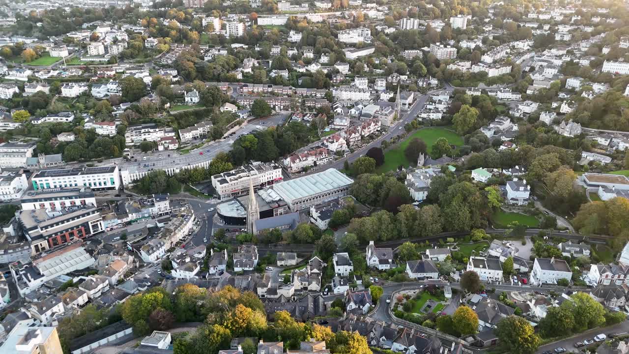 Cinematic aerial drone view of Torquay town center showcasing residential buildings streets trees and urban landscape during early morning in Devon England