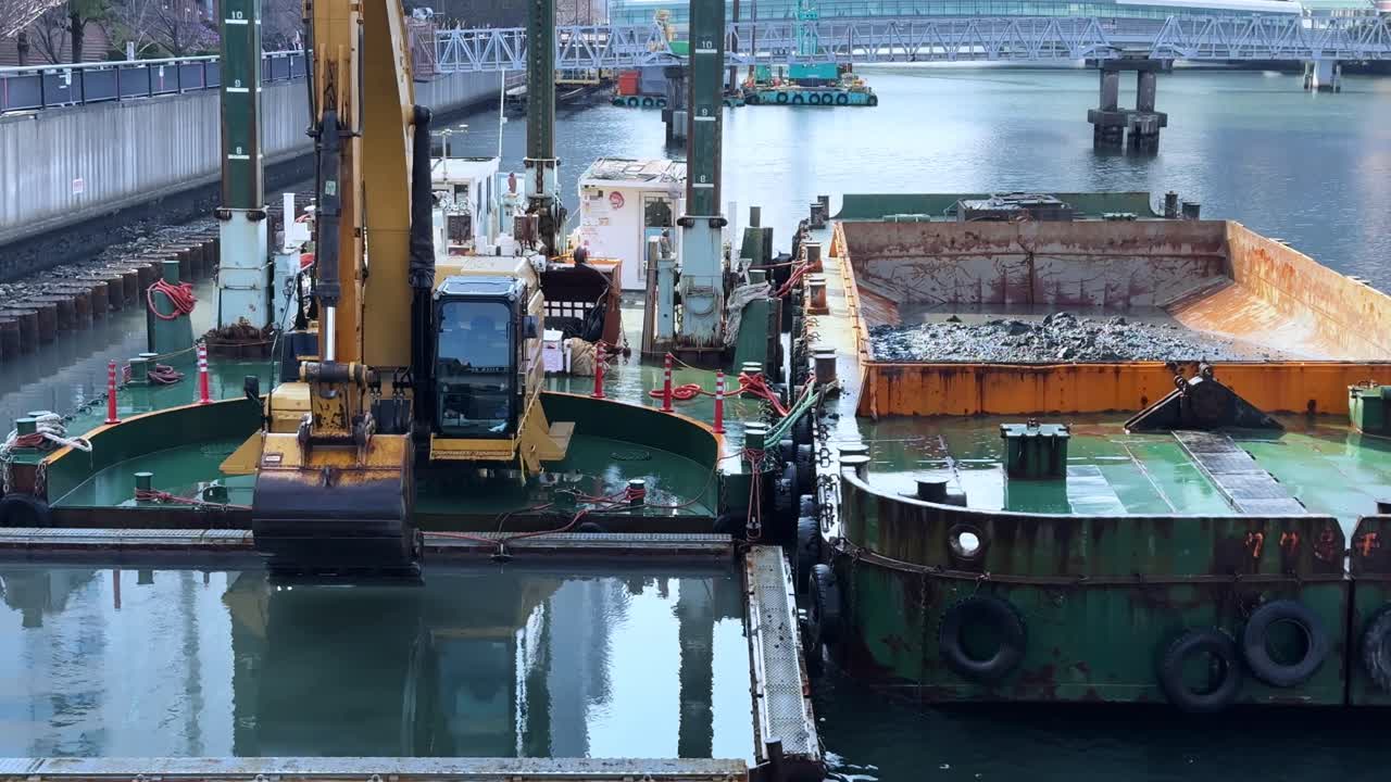 A crane working on a floating platform near a barge in Harumi, Tokyo