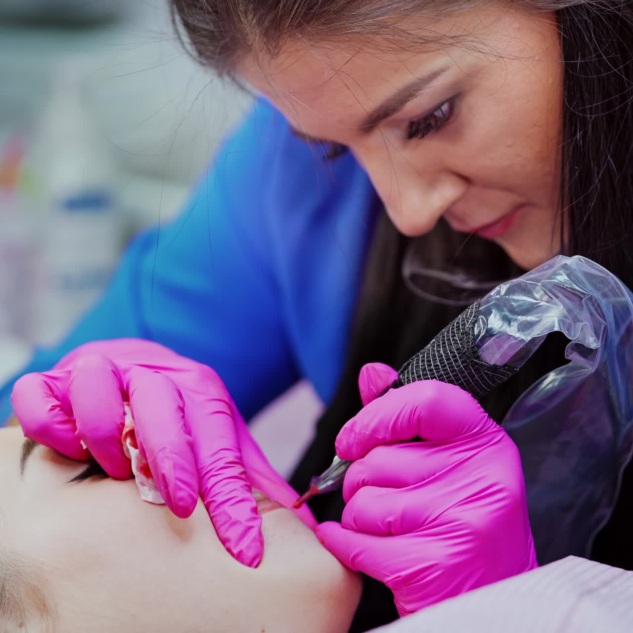 Lips pigmentation process. Professional tattooist doing permanent make-up on woman's lips in a beauty salon. Cosmetology concept.