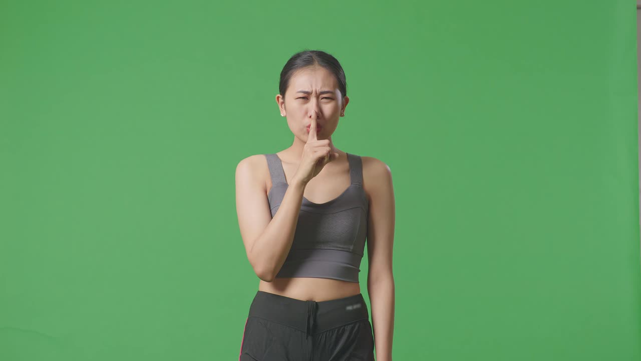 스포츠 의류 를 입은 여자 가 조용 한 몸짓 을 하고 있다