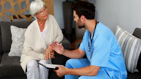 Doctor-and-senior-woman-discussing-over-clipboard