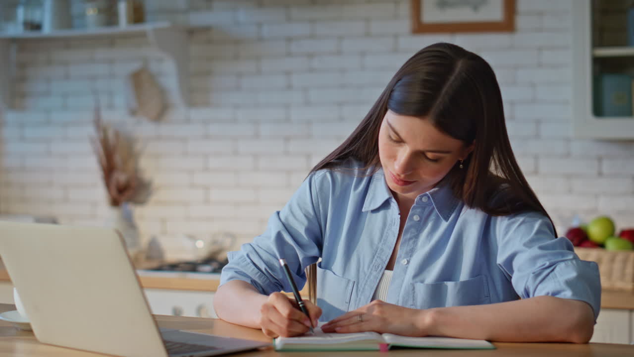 chica enfocada estudiando en línea en casa cocina de cerca. mujer estudiante tomando notas