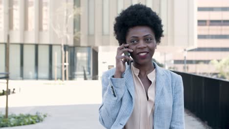 beautiful smiling businesswoman talking on phone on street