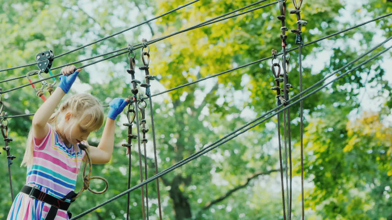 entretenimiento en el campamento de verano - un niño aprende a usar cables de seguros trepa alto en las ramas de