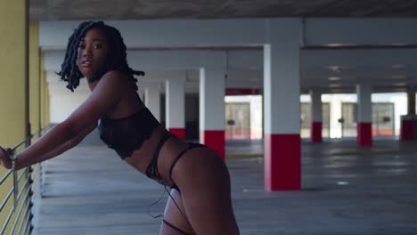 lingerie model close up as an african girl is bent over the railing of a parking garage