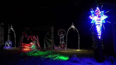 Weihnachtliche-Vereiste-Skulptur-Krippe-Auf-Einem-Bett-Aus-Schnee-An-Einem-Winterabend-Neonhelle-Led-lichter,-Die-Einen-Unglaublichen-Erleuchtenden-Davidsstern-Anstrahlen,-Umrahmt-Von-Einem-Kerzenrad,-Leuchtend-Glänzend