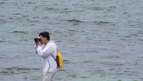 young-asiatic-professional-freelancer-photographer-taking-photo-and-pictures-at-ocean-sea