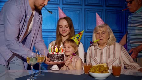 Mädchen-Feiert-Geburtstagsparty-Mit-Eltern,-ältere-Großelternfamilie-Bläst-Kerzen-Auf-Kuchen-Aus