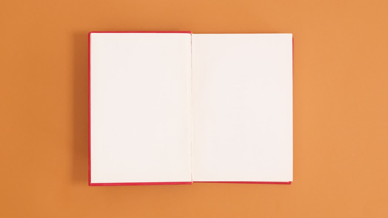 Red vintage hardcover book appear and open with copy space on orange background. Stop motion flat lay