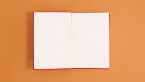 el libro de tapa dura de época roja aparece y se abre con espacio de copia en fondo naranja.