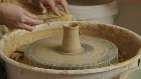 medium close up shot of cleaning a potters wheel after finishing a small vase