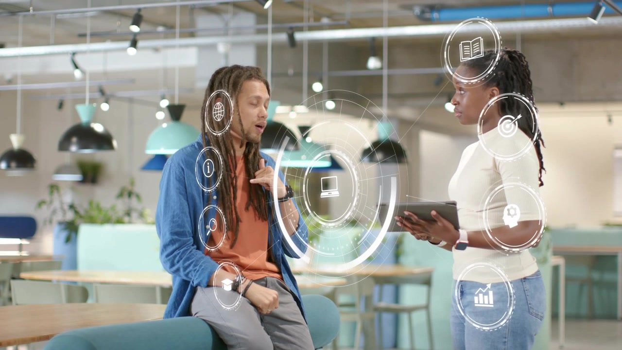 Man sitting on bench in office speaking shifting HUD highlighting icons while woman holding tablet