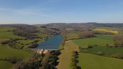 4k-Volando-Sobre-El-Embalse-De-Hawkridge,-Drone-Avanzando-Sobre-El-árbol-Verde-Frente-A-La-Pared-De-La-Presa-De-Agua,-60fps