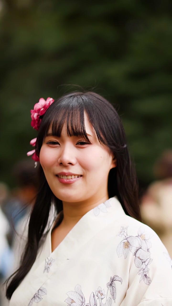 Primo piano di una donna giapponese in kimono bianco che sorride all'aperto al Meiji Jingu