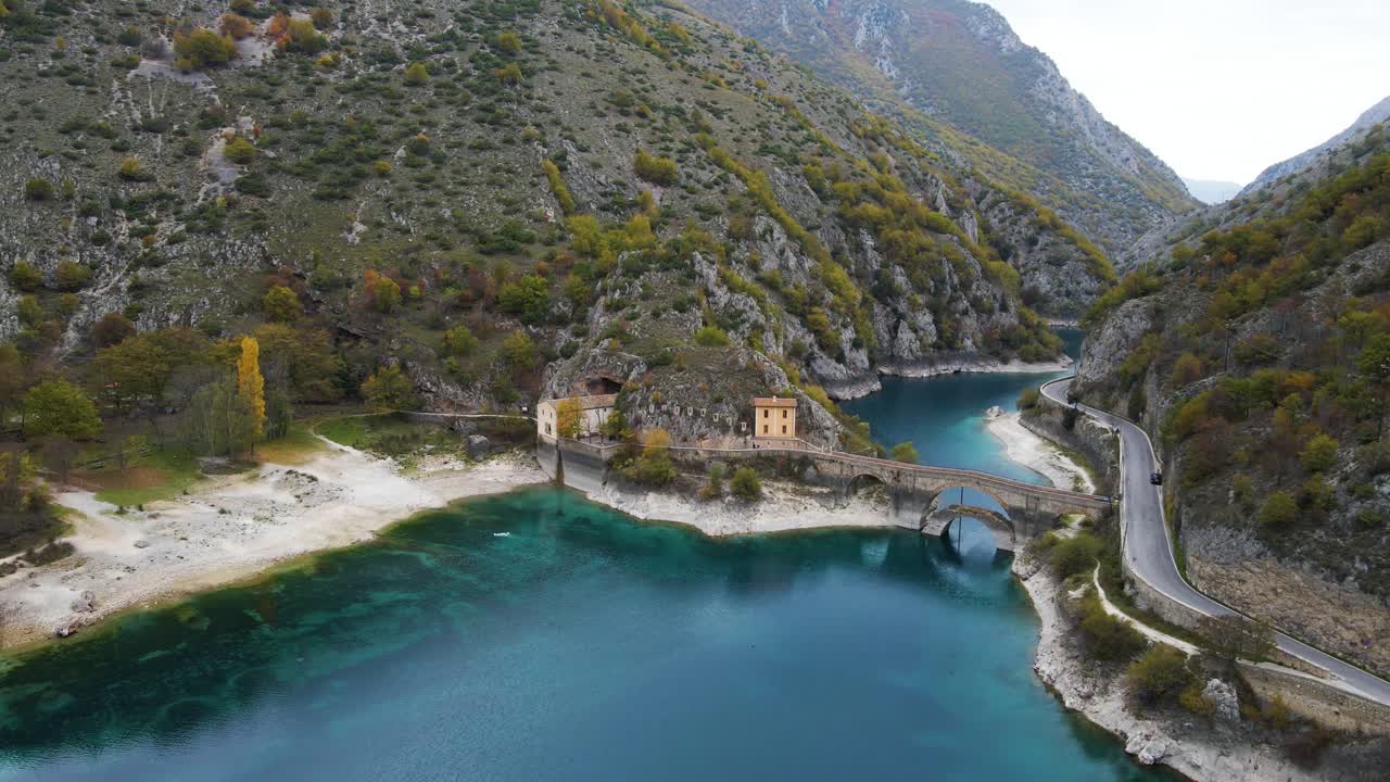 Splendida vista aerea della gola del fiume Sagittario, caratterizzata da acqua glaciale turchese, un ponte ad arco in pietra storico, vecchi edifici di mulini annidati in uno spettacolare canyon calcareo con il fogliame autunnale