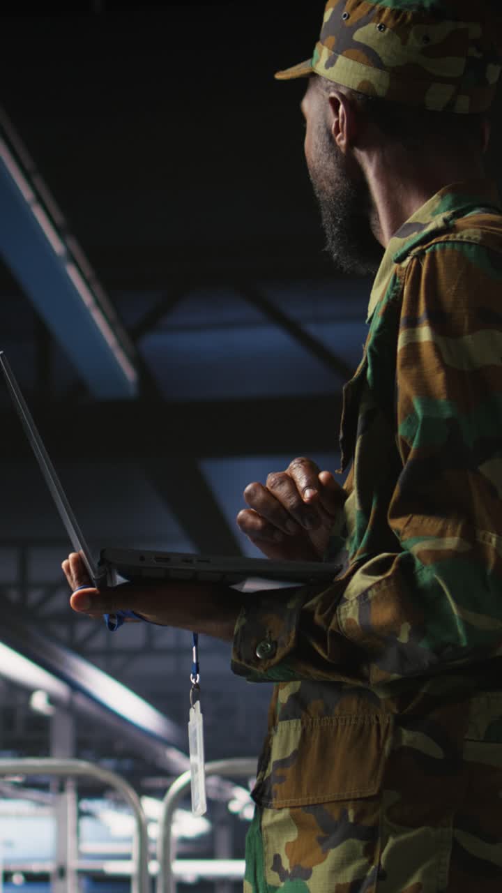 Vertical video Army technician in command center server room using laptop
