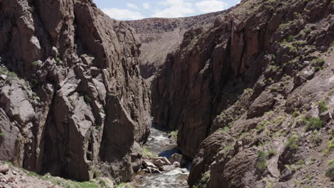 Owens-river-gorge-with-flowing-river-surrounded-by-rugged-cliffs-on-a-sunny-day,-aerial-view