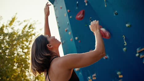 Ein-Blondes-Mädchen-Mit-Bob-Frisur-Plant,-Wie-Sie-An-Einem-Sonnigen-Sommertag-Beim-Klettern-Eine-Route-Entlang-Einer-Kletterwand-Zurücklegen-Wird.-Ein-Blondes-Klettermädchen-Mit-Bob-Frisur-In-Einem-Schwarzen-Oberteil-Plant-Ihre-Route-Entlang-Der-Kletterwand-Und-Platziert-Ihre-Hände,-Als-Würde-Sie-Sie-Auf-Lote-Legen-