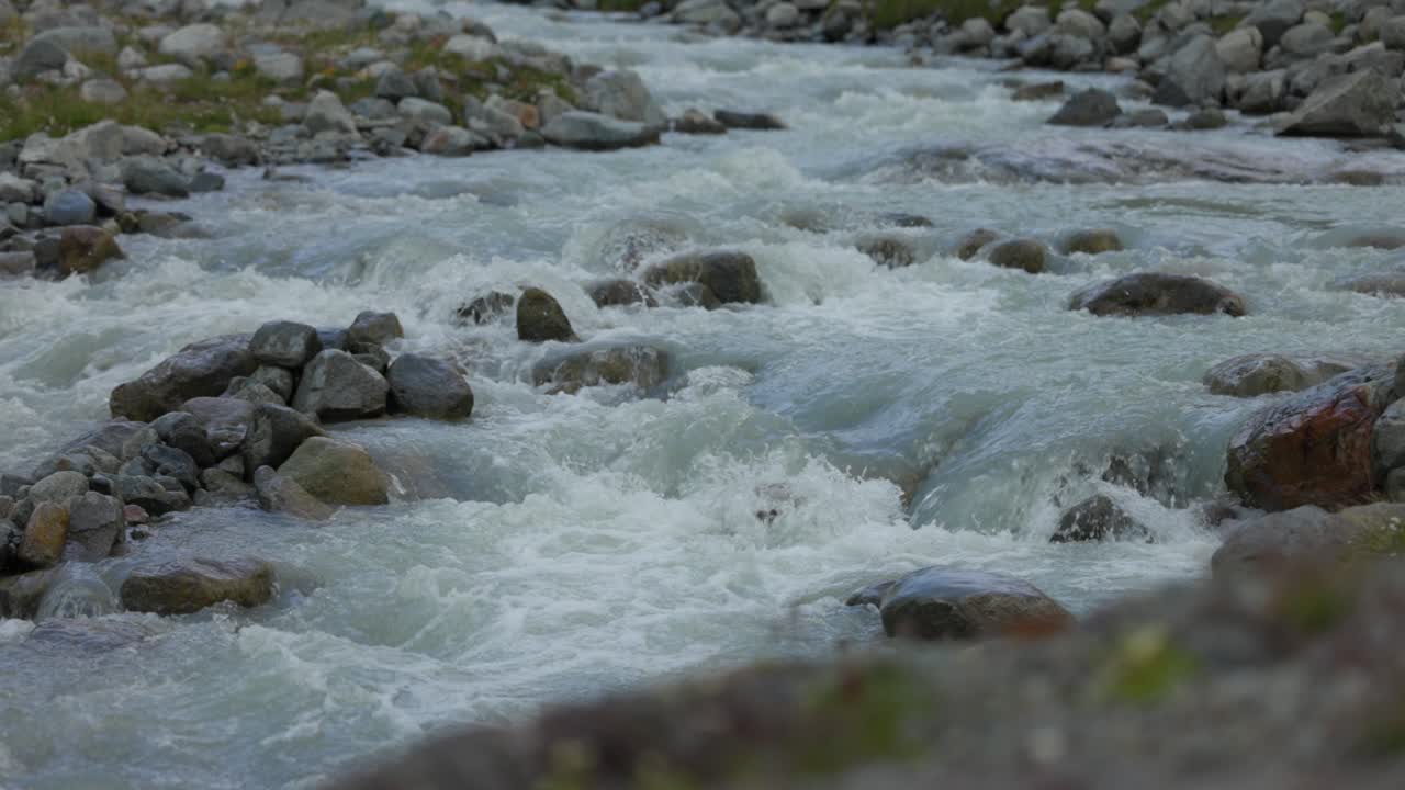 Ruscello di montagna che scorre impetuoso in Valmalenco, bassa profondità di campo, di giorno.