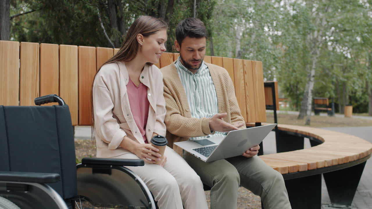 Couple Working on a Laptop in a Park with a Wheelchair