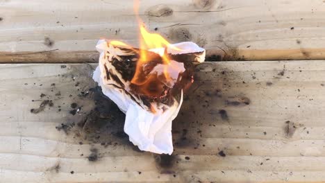 closeup view of person setting tissue on fire using friction on wood