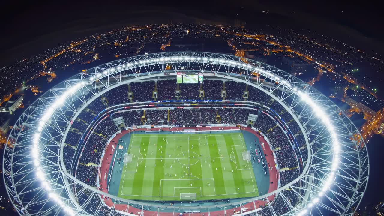 Aerial view video of a brightly lit stadium at night, showcasing a soccer match