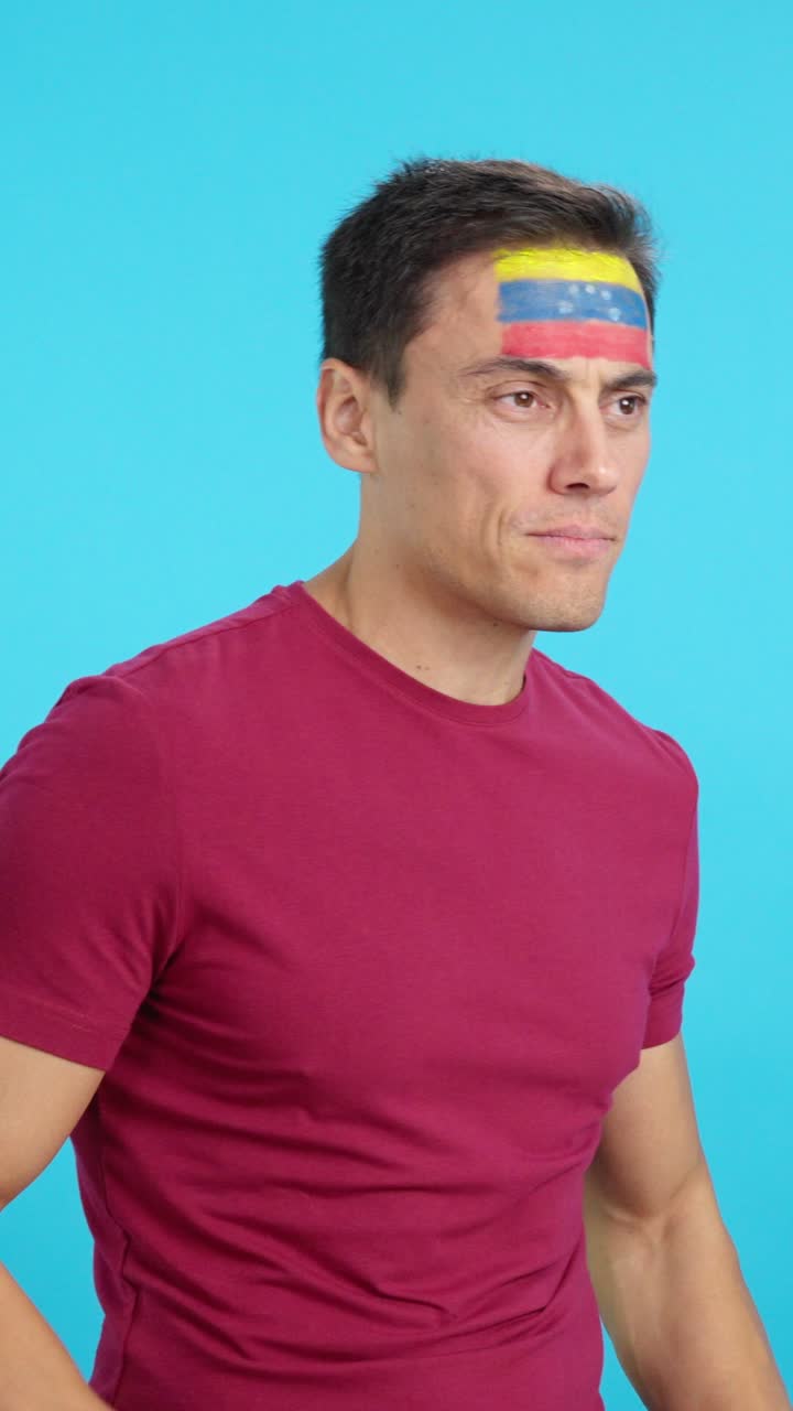 Happy man with venezuelan flag painted on face looking away