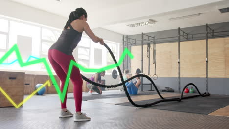animación de datos de procesamiento de gráficos sobre mujer caucásica entrenamiento cruzado con cuerdas de batalla en el gimnasio