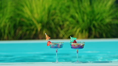 two colorful cocktails by the pool