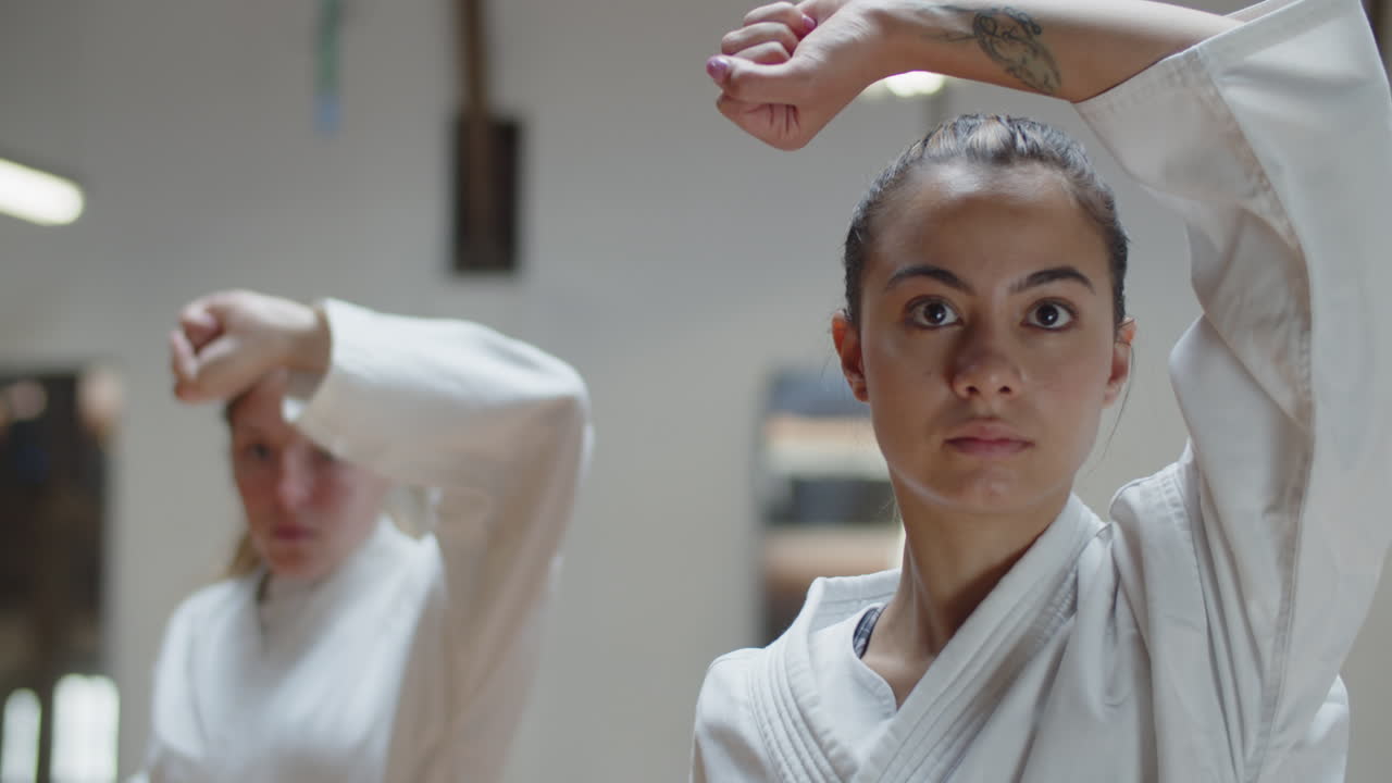 체육관에서 가라데 포즈를 보여주는 기모노를 입은 소녀의 클로즈업 샷