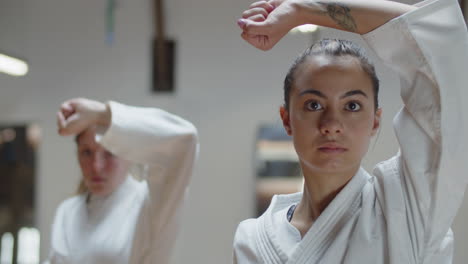 close-up shot of girl in kimono showing karate pose in gym