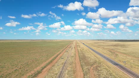 el interior de queensland en un día nublado a lo largo de una carretera y vías de tren