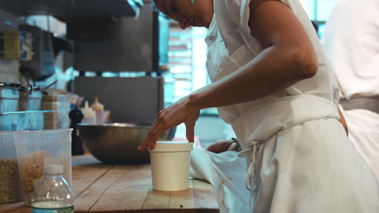 Woman packaging food for take away at a deli,cafe, side view