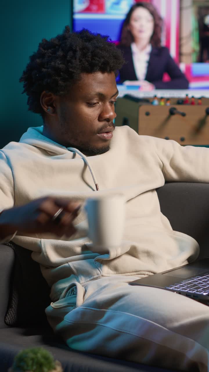 African American Man Working on Laptop and Drinking Coffee on Couch