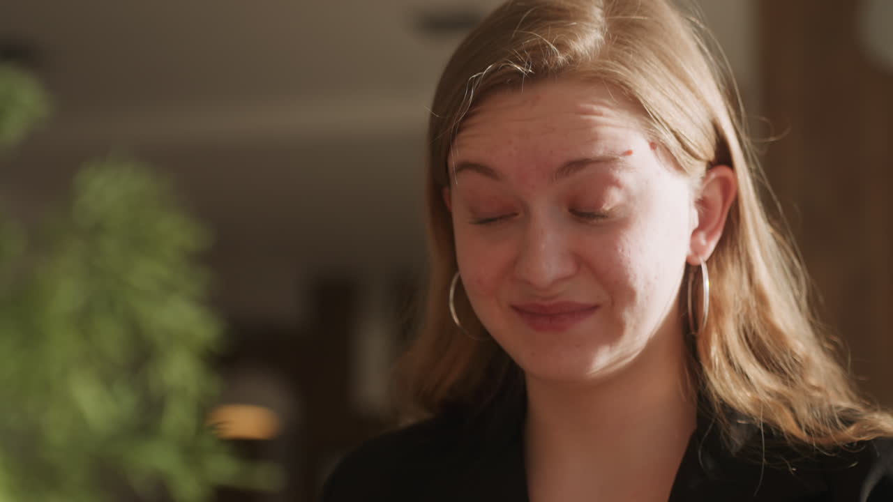 Primo piano di donna bianca che assaggia caffè amaro, fronte aggrottata e smorfia in un caffè al chiuso, luce solare e piante sullo sfondo, valutazione espressiva del sapore, reazione spontanea in stile recensione