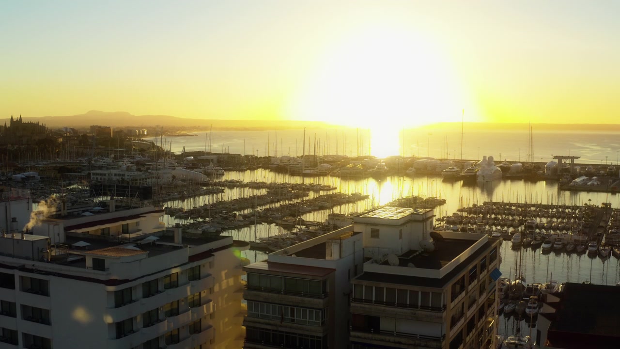 Drone desliza para a direita revelando a marina e o porto de Palma na hora dourada em Maiorca