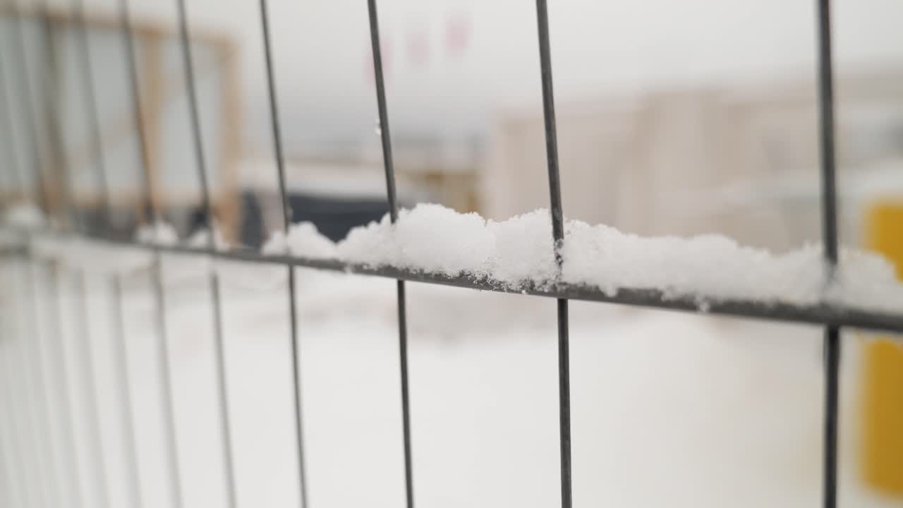 mirando a través de la valla de rionet en el sitio de construcción, donde hay nieve por todas partes