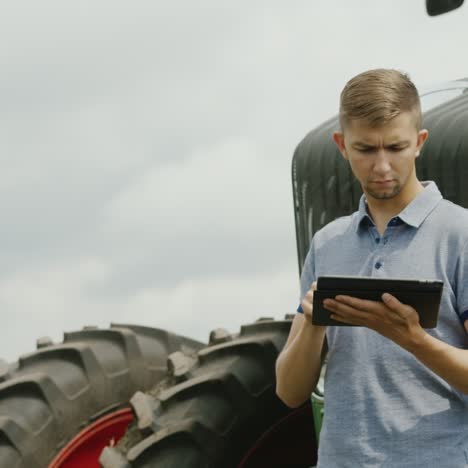 un joven agricultor caucásico está trabajando en el campo con una tableta 3