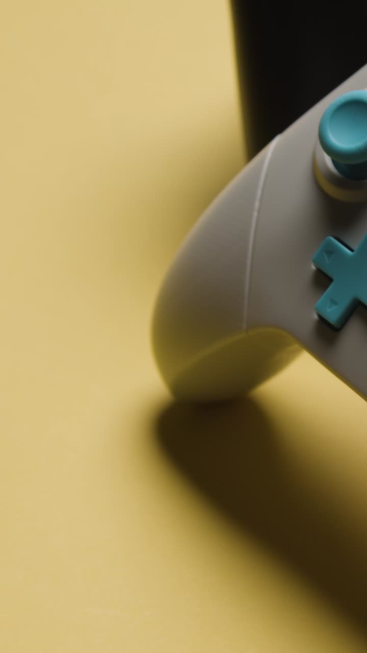 Vertical Video Close Up Hand Picking Up Video Game Controllers Yellow Background