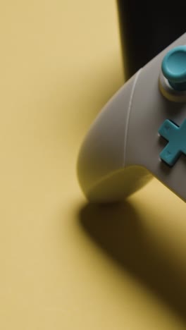 Vertical-Video-Close-Up-Hand-Picking-Up-Video-Game-Controllers-Yellow-Background