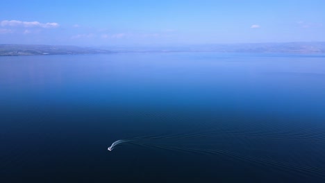 the sea of galilee on a pastoral sunny spring day,
a sports boat races through the calm waters