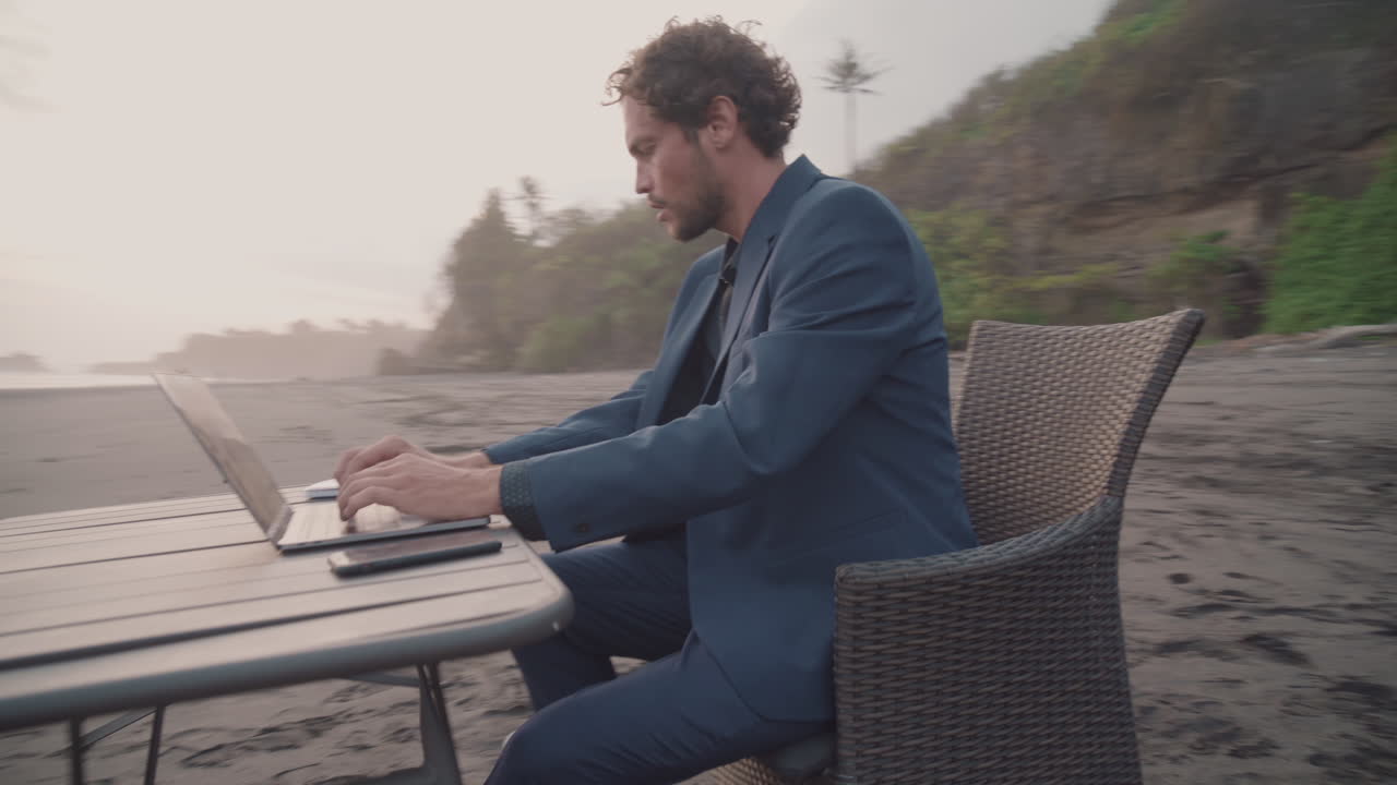 Uomo che lavora al laptop in spiaggia