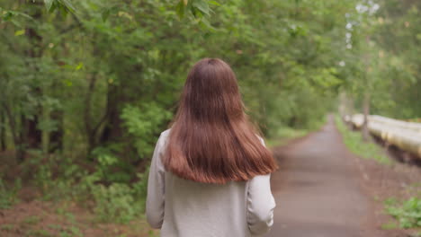 a woman walking and running through a forest path