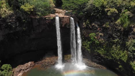 aerial crane rise and tilt down of wailua falls in kauai, hawaii. with rainbow reflection in the water.