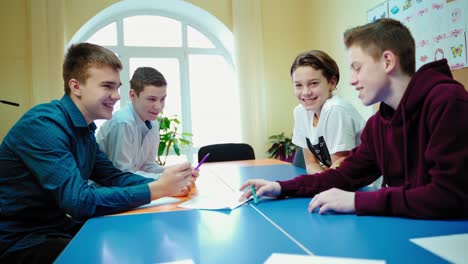 education at school. boys working in group at the lesson. teenage children talking together in the modern classroom.