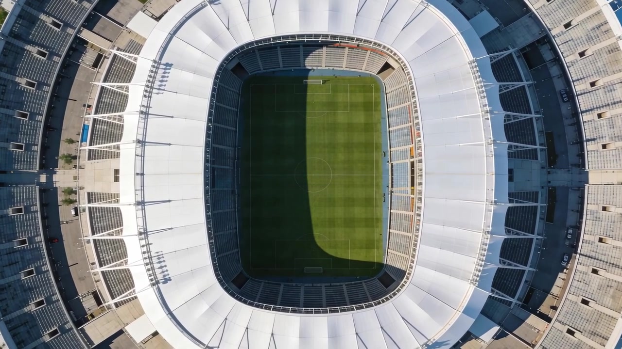 Un pallone da calcio emerge sfrecciando in diagonale sopra uno stadio ovale, con la telecamera che si posiziona sul campo in erba.