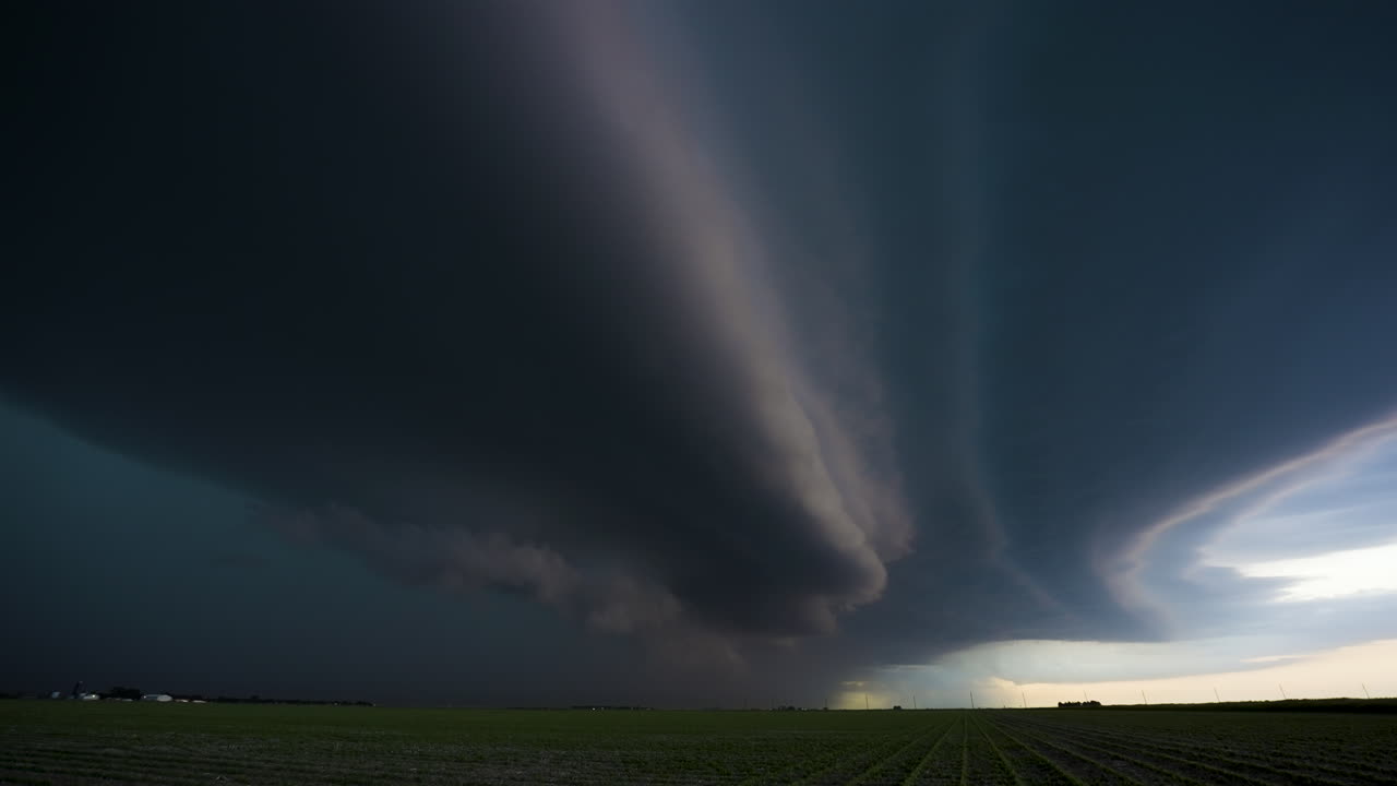 A powerful dark shelf cloud moves across beautiful farmland fields